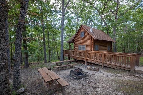 A rustic Outpost cabin under shade trees at Lake of the Ozarks State Park