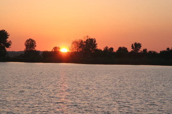 the brght orange sun setting behind the lake
