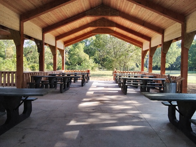 Rows of picnic tables under the roof of the open picnic shelter