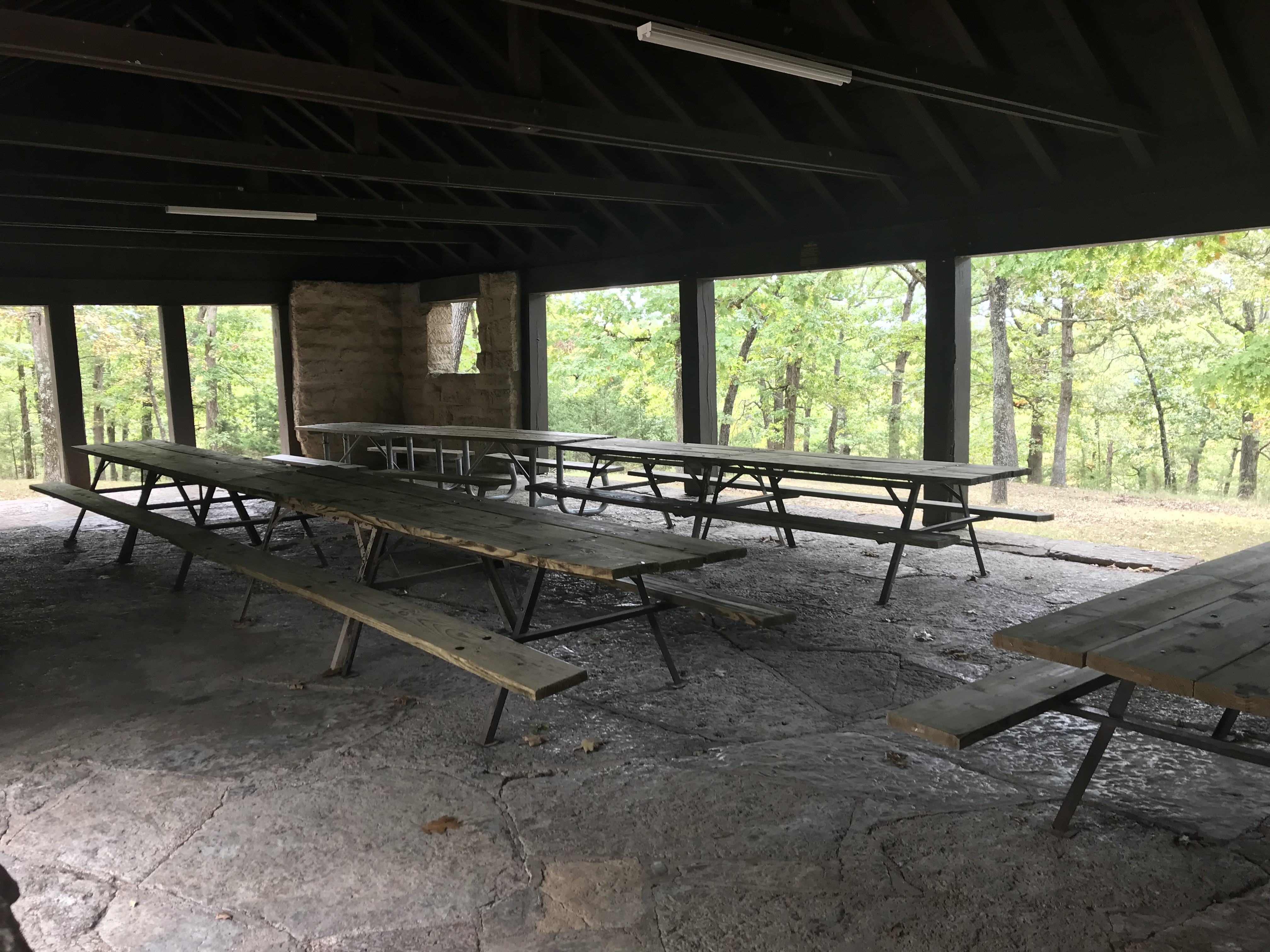Picnic tables on stone floor inside the open picnic shelter
