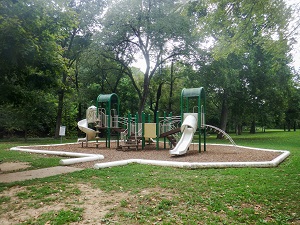 playground aparatus with slides and other activities with mulch base and paved pathway