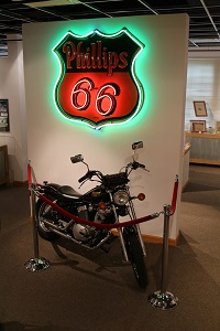 a motorcycle stands below a Phillips 66 sign inside the visitor center