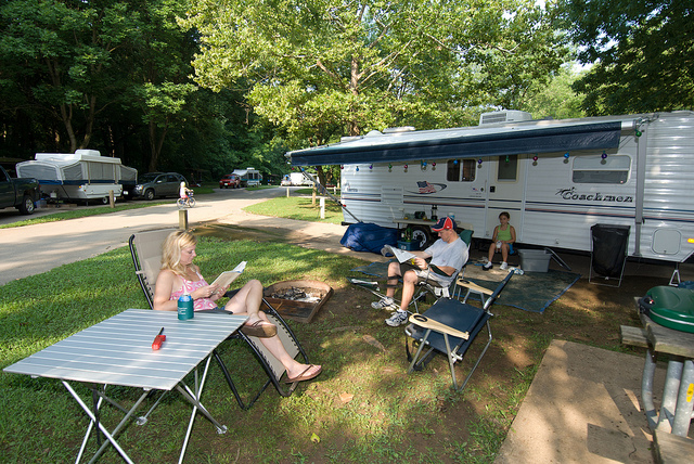 people sitting and reading in front of their camper