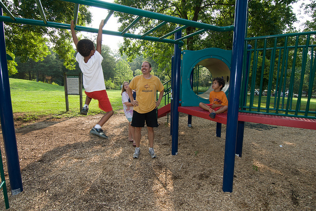 a boy plays on the monkey bars while others watch
