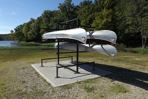 three canoes on a rack by the lake