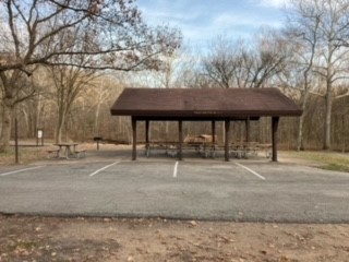 Pavilion-style open shelter with paved parking lot in foreground