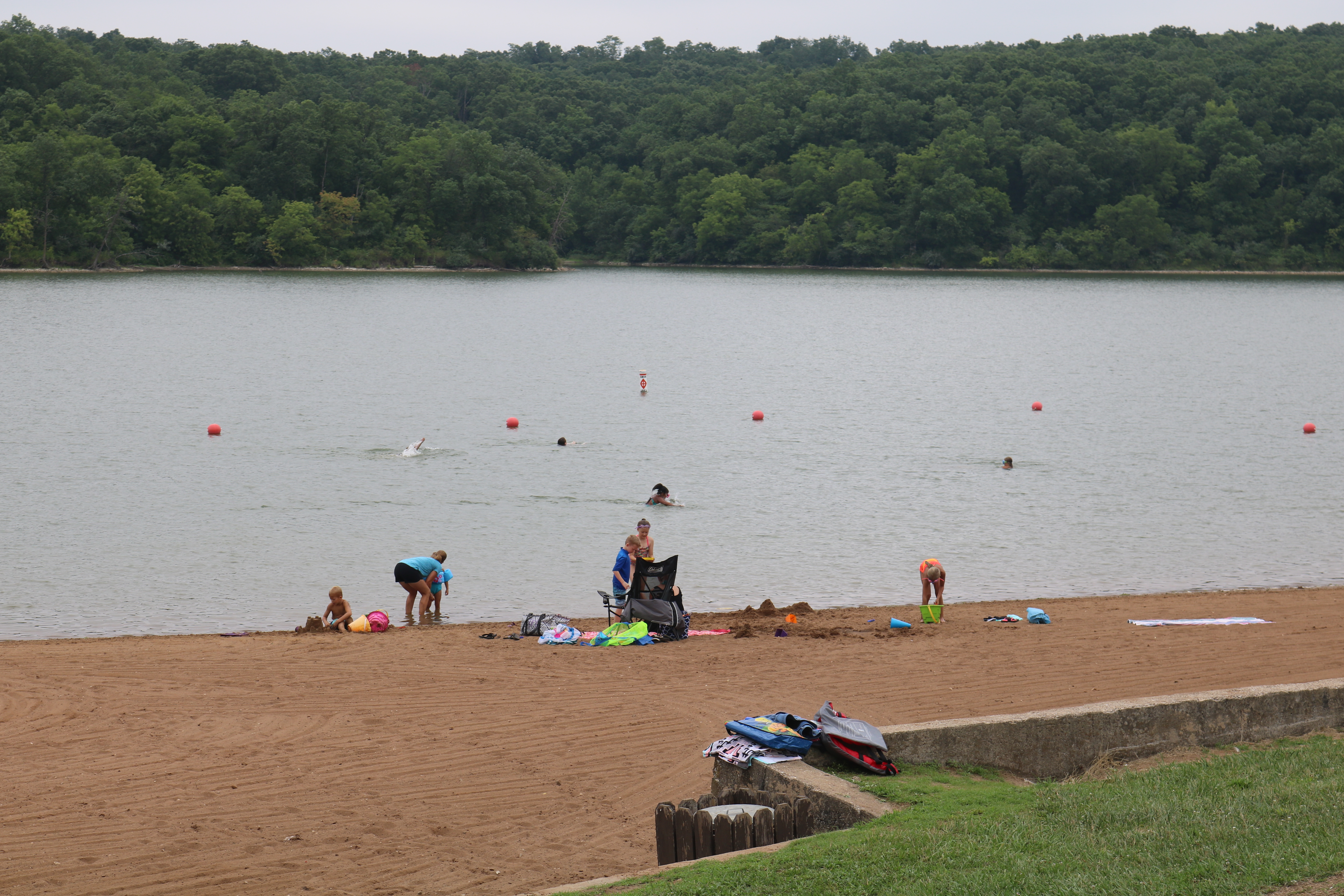 people on the beach and swimming in the lake