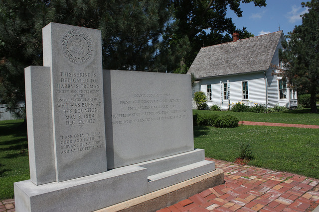 an inscribe monument dedicated to Harry S Truman with his birthplace home in the background