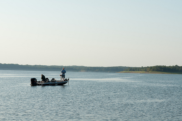 two people fishing from a boat on the lake