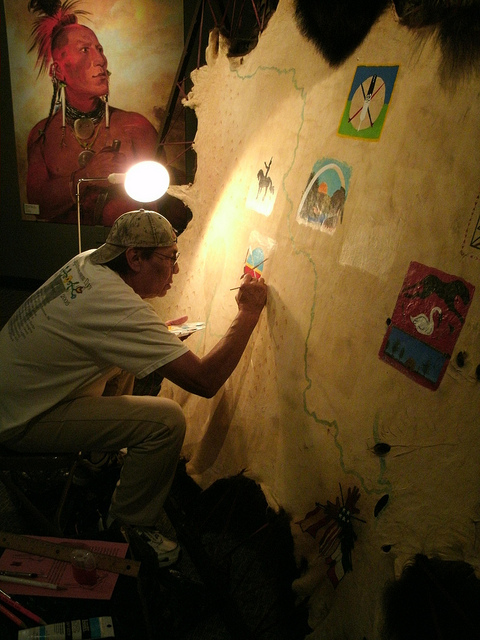 A Native American works on a project to represent his tribe inside the visitor center