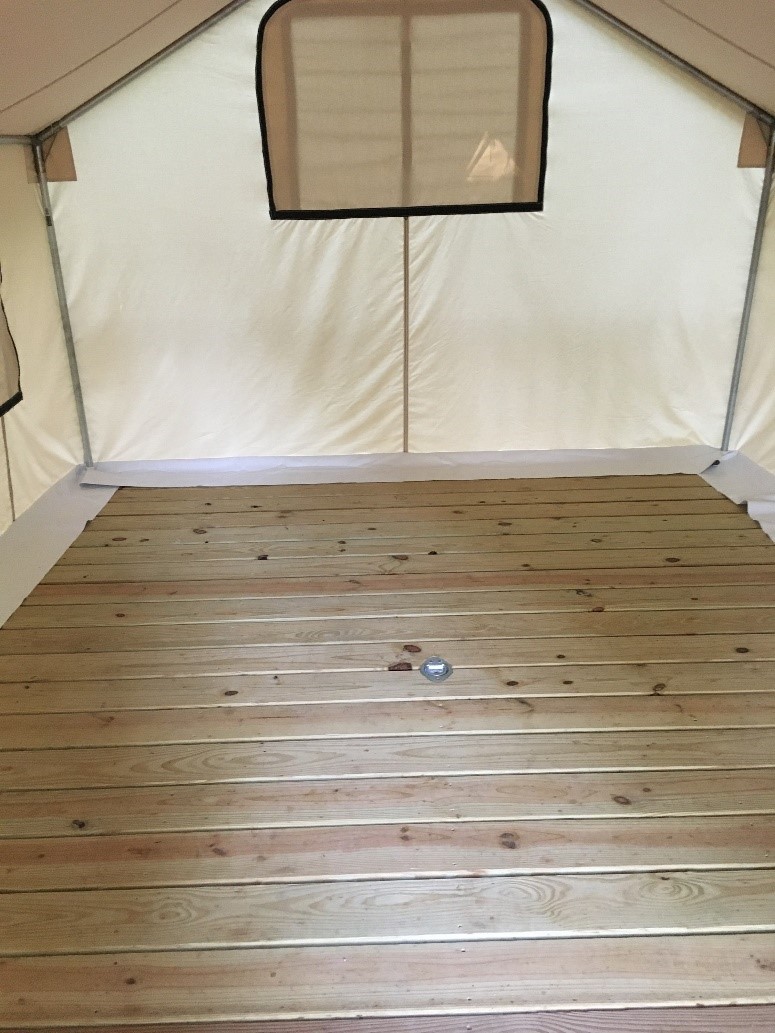 Surface of wooden platform inside a beige canvas tent