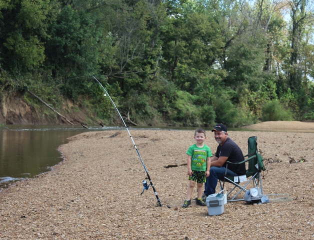 a man and a little boy fishing on the river bank