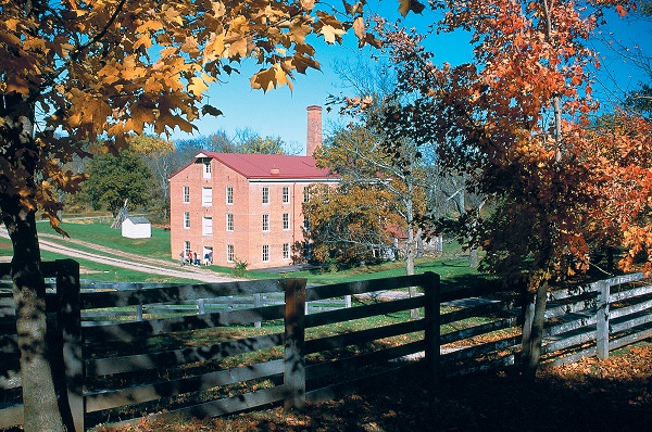 four story, red brick mill surrounded by fall colors