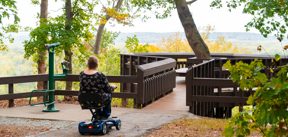 Woman in motorized wheelchair enjoying the view on a wooden overlook