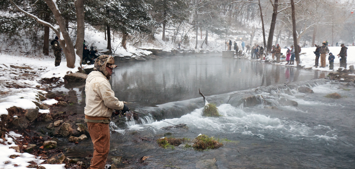 People fishing along the river in winter.