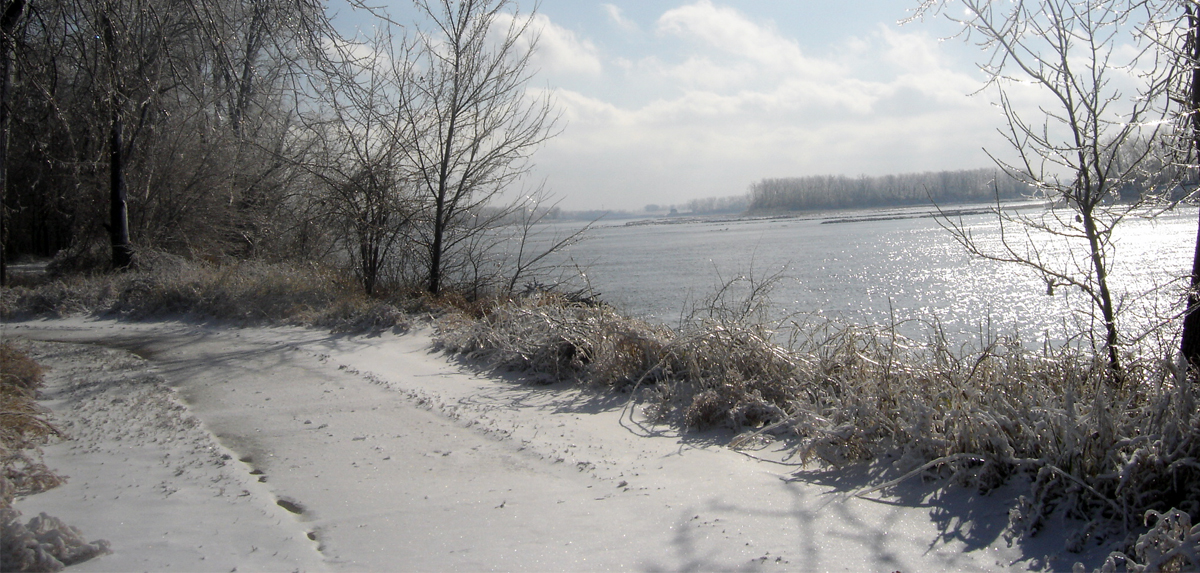 Walking path covered with snow and ice next to river